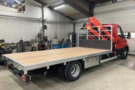 Rode vrachtwagen met open laadbak in een werkplaats voor carrosserie en wagenbouw.