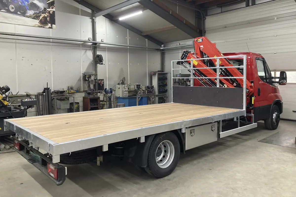 Rode vrachtwagen met open laadbak in een werkplaats voor carrosserie en wagenbouw.