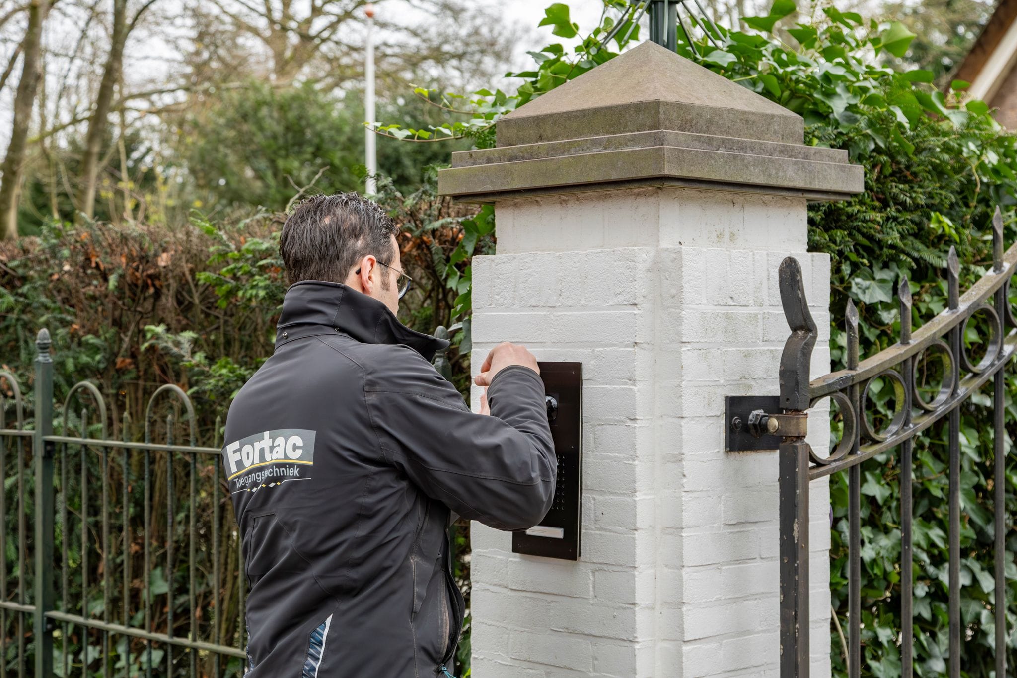 Monteur met Fortac-jas bedient intercom bij toegangspoort