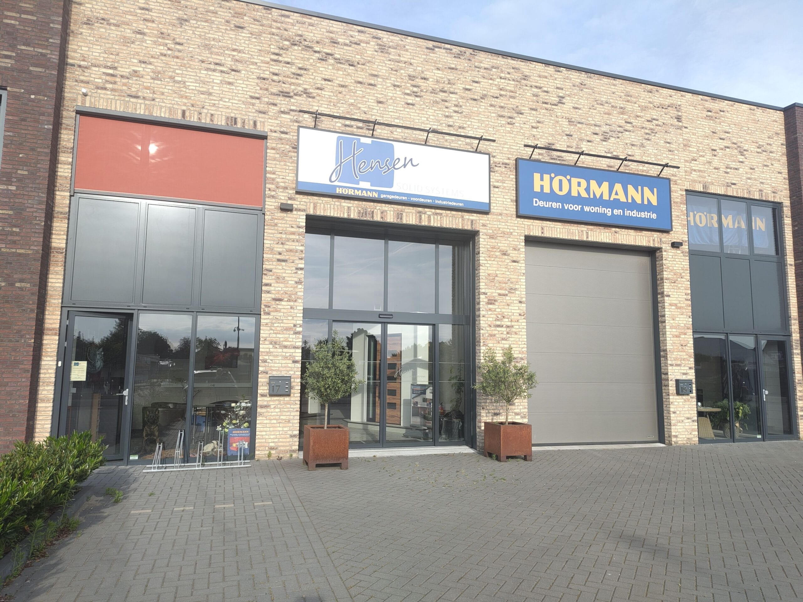 Bedrijfsgevel met Hensen- en Hormann-borden boven de toegang