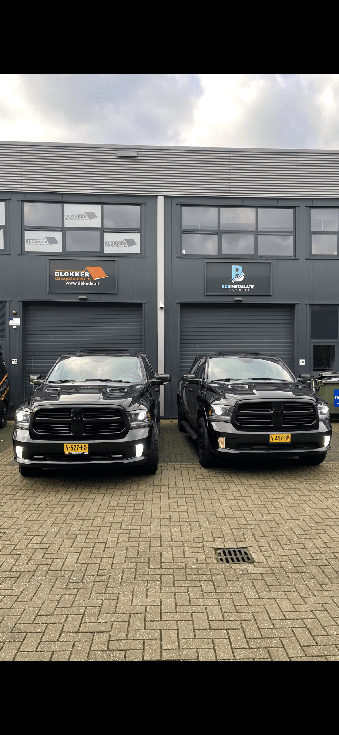 Bedrijfspand van Blokker Daksystemen met twee zwarte bedrijfswagens ervoor