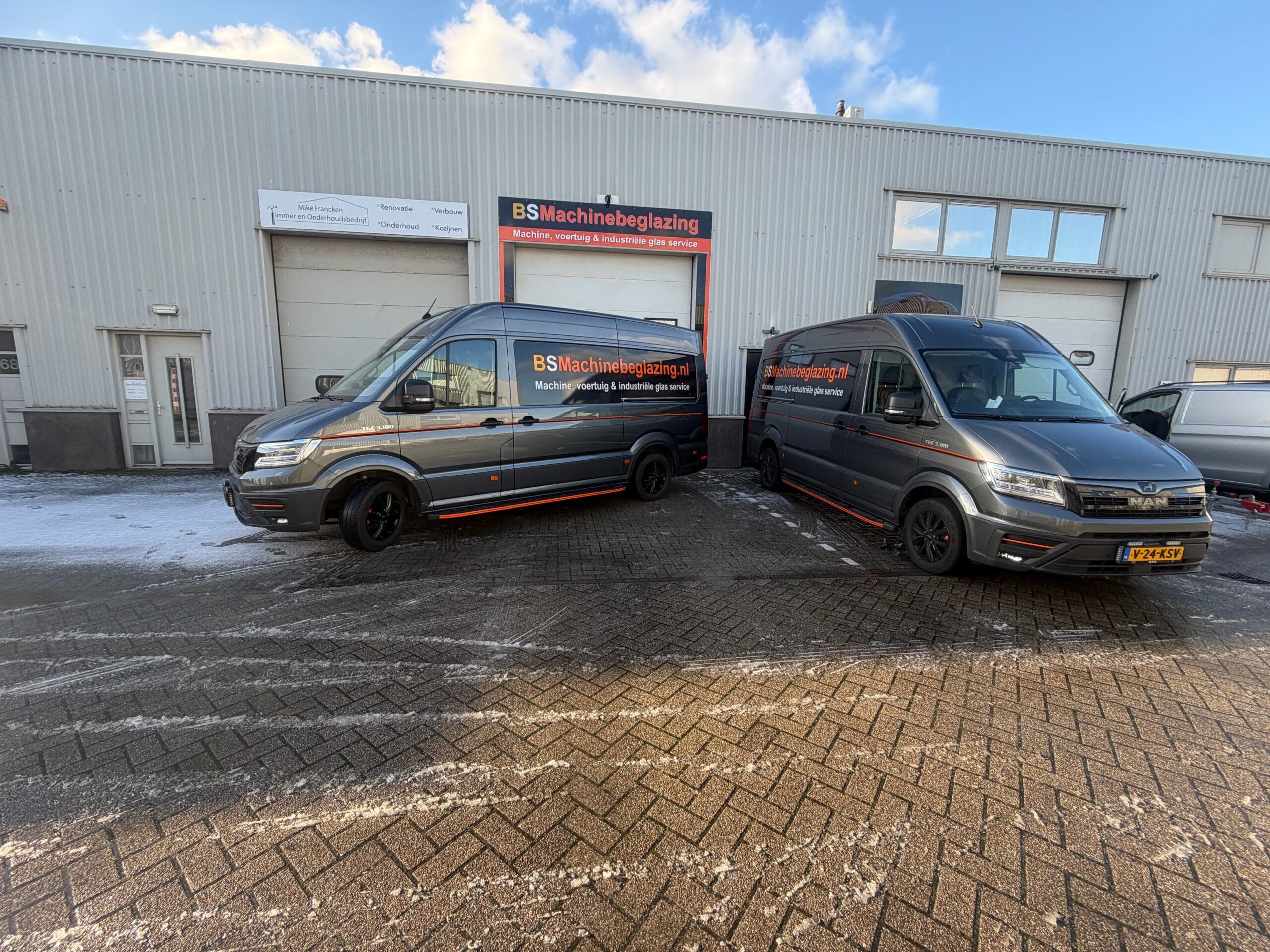 Twee bestickerde bedrijfsbussen van BS Machinebeglazing voor het bedrijfspand