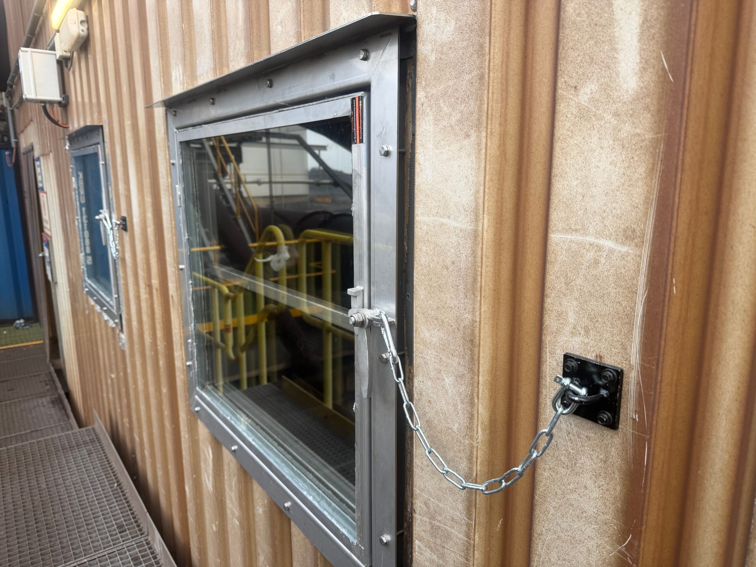 Metalen raam met ketting bevestiging in golvende industriele gevel