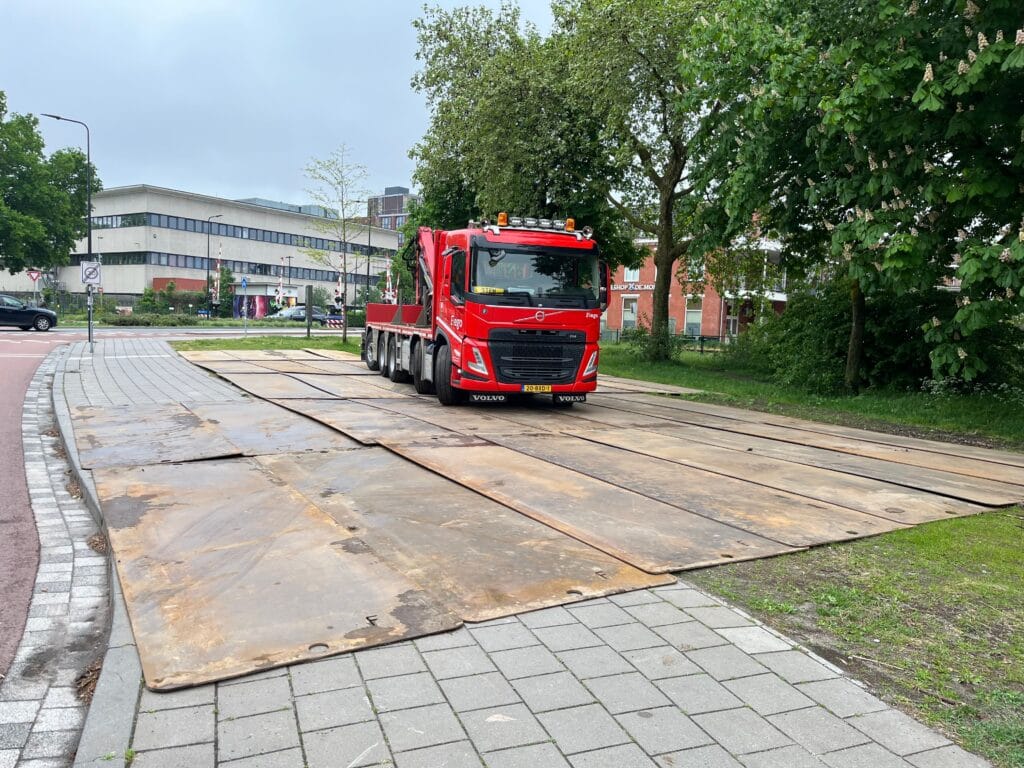 Rode vrachtwagen staat op stalen rijplaten op straat