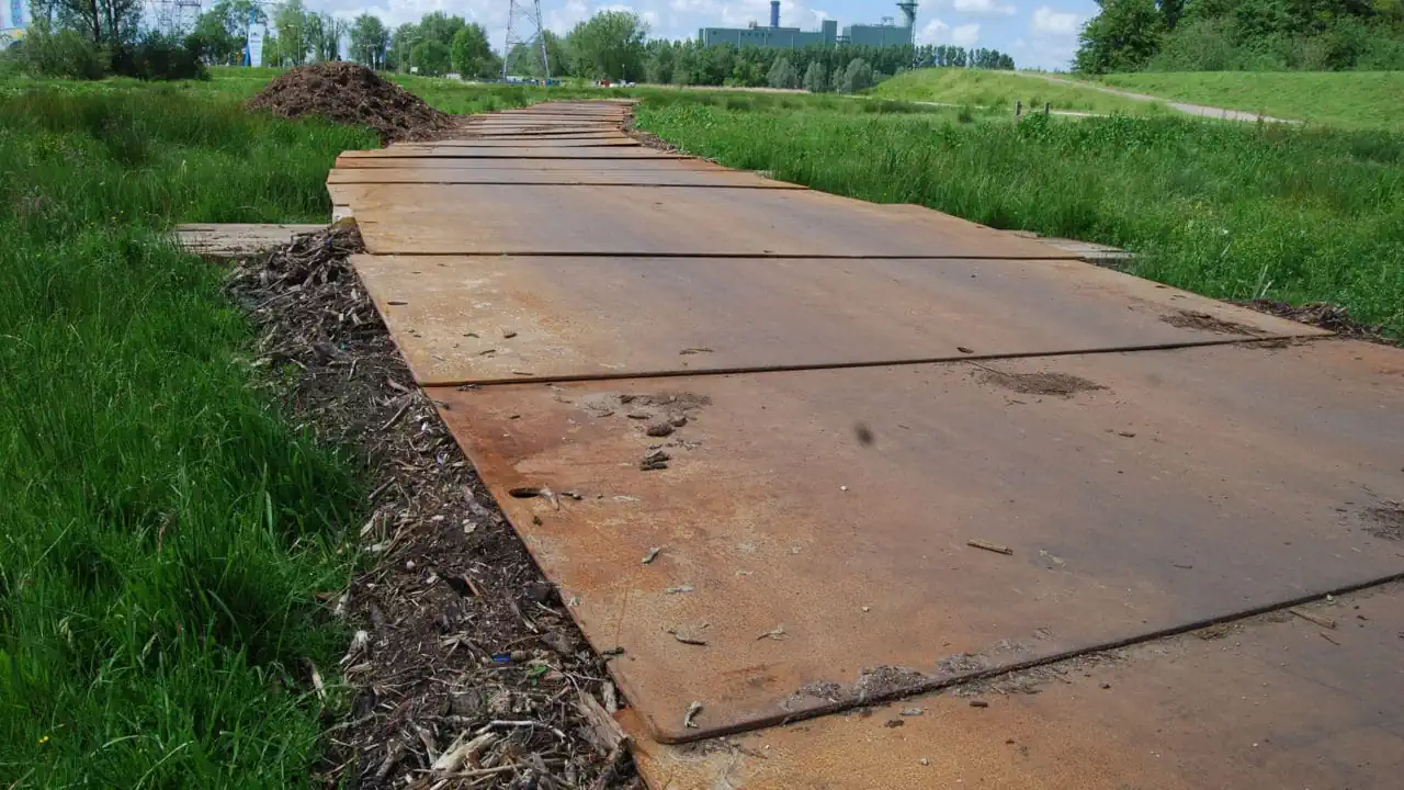 Rijplaten op grasveld vormen tijdelijk pad op bouwterrein