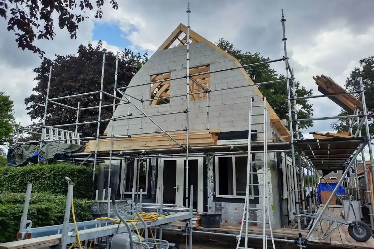 Woningbouw in uitvoering met steigers, open gevels en bouwmaterialen