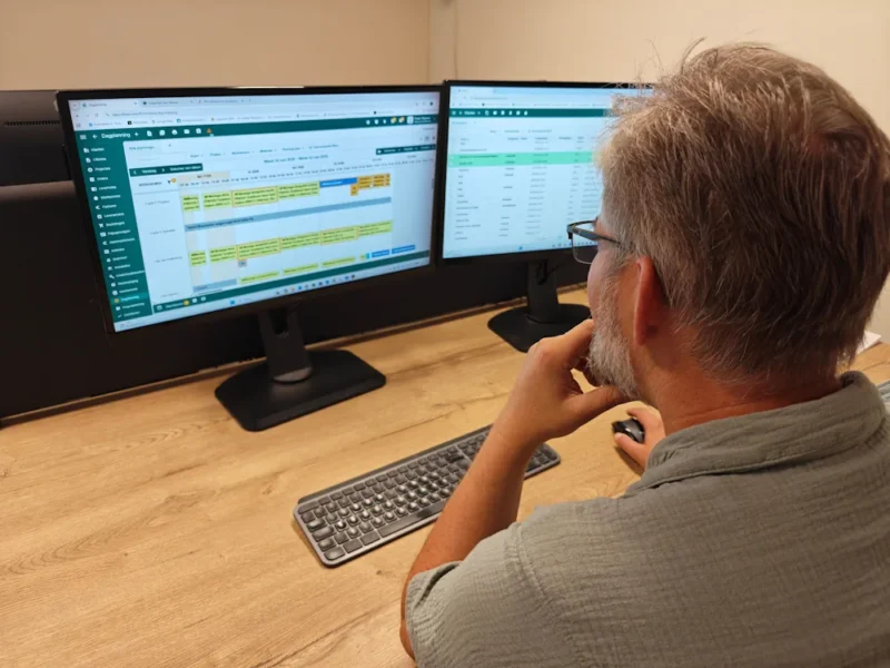 Medewerker van Sfeervol Buitenleven achter twee computerschermen met bedrijfssoftware.